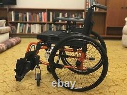 Black and orange frame Care Co wheelchair. Lightweight and foldable. Good design